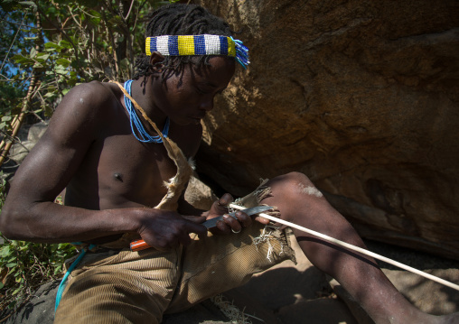 Tanzania, Serengeti Plateau, Lake Eyasi, hadzabe bushman making the arrow for a hunting bow