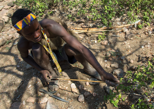 Tanzania, Serengeti Plateau, Lake Eyasi, hadzabe bushman making the arrow for a hunting bow