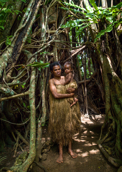Woman with her baby in traditional skirt standing under a banyan tree, Efate Island, Port Vila, Vanuatu