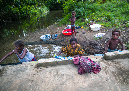 Woman and kids doing laundry in river, Shefa Province, Efate island, Vanuatu