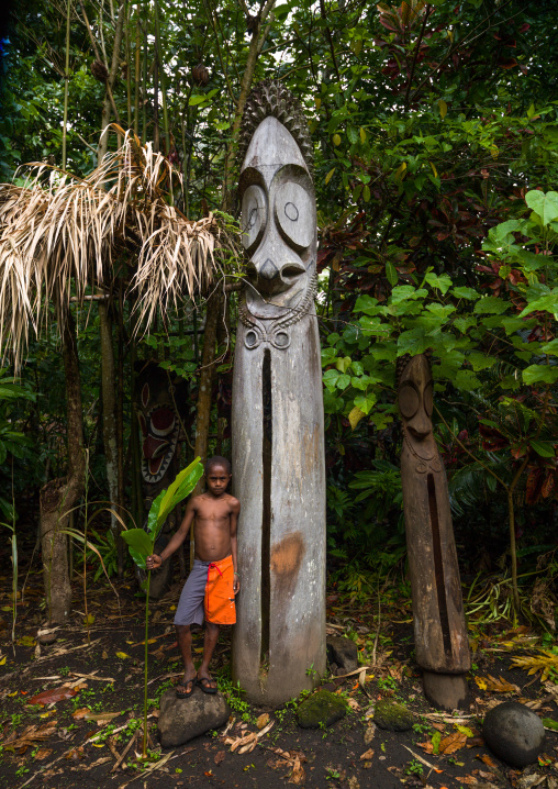 Ni-Vanuatu boy standing in front of slit gong drums in the jungle, Ambrym island, Olal, Vanuatu