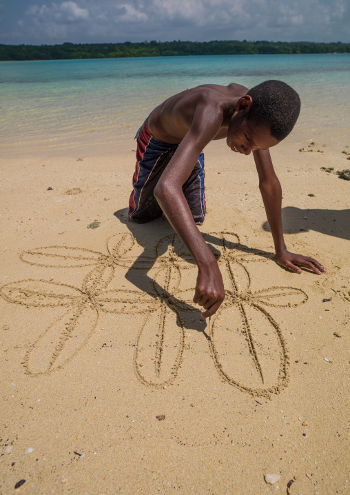Boy on the beach making a traditional sand drawing, Sanma Province, Espiritu Santo, Vanuatu