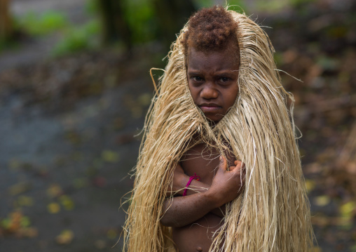 Young girl protecting herself from the rain with a traditional grass skirt, Tanna island, Yakel, Vanuatu