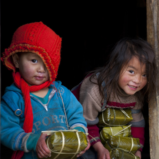 Black hmong kids holding wrapped rice cakes for tet, Sapa, Vietnam