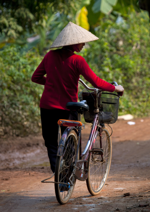 Woman with a sedge hat pushing her bike, Sapa, Vietnam