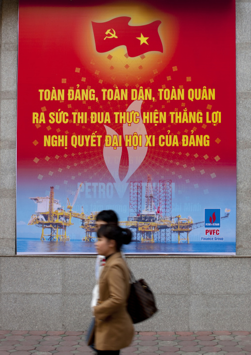 Couple passing by a propaganda billboard of the communist party, Hanoi, Vietnam