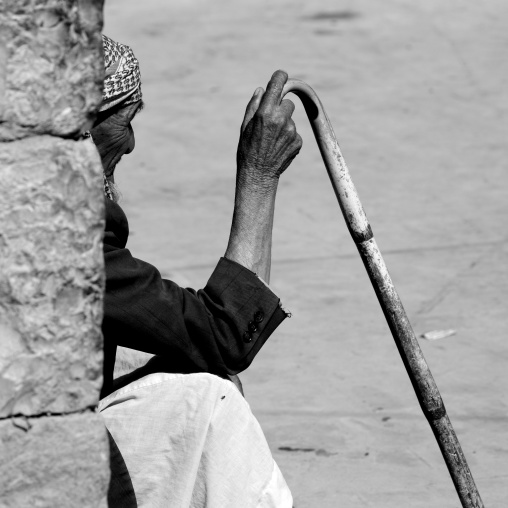 Old Man Sitting Against A Wall And Holding A Cane In Shibam, Yemen