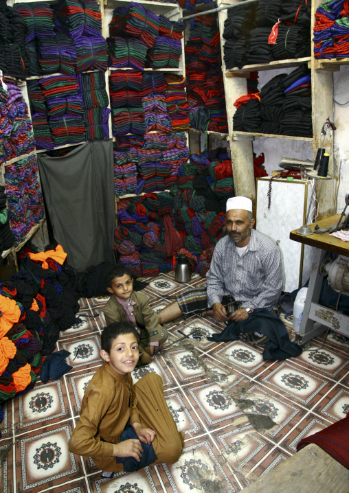 Shopkeeper With Two Kids Sitting On The Ground In Sanaa Old Souq, Yemen