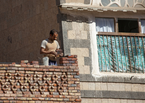 Yemeni worker putting bricks on a wall, Amanat Al-Asemah, Sanaa, Yemen