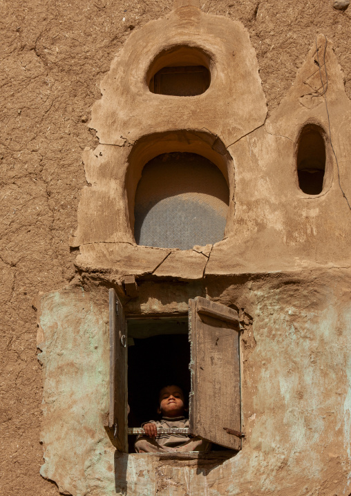 Yemeni girl at the window of a mudbrick house, Amran Governorate, Amran, Yemen