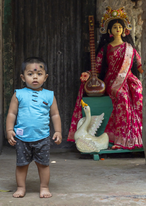 Boy standing in front of a hindu statue of goddess Saraswati, Dhaka Division, Munshiganj, Bangladesh