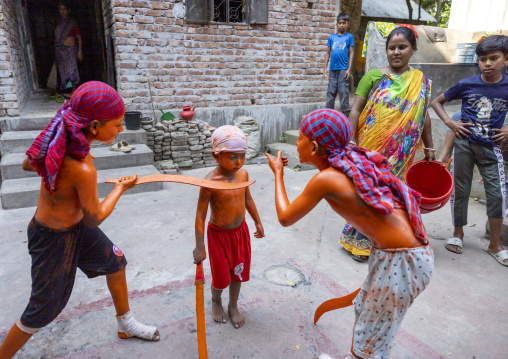Young hindu devotees in orange color playing with swords at Lal Kach festival, Dhaka Division, Munshiganj, Bangladesh