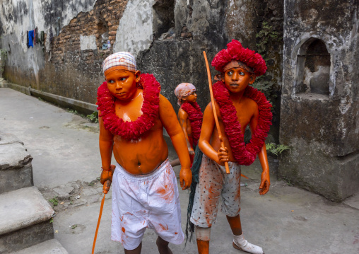 Young hindu devotees in orange color playing with swords at Lal Kach festival, Dhaka Division, Munshiganj, Bangladesh