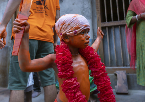 Young hindu devotee in orange color playing with sword at Lal Kach festival, Dhaka Division, Munshiganj, Bangladesh