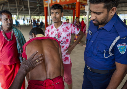 Policeman looking the back of a man who performed body suspension, Sylhet Division, Kamalganj, Bangladesh