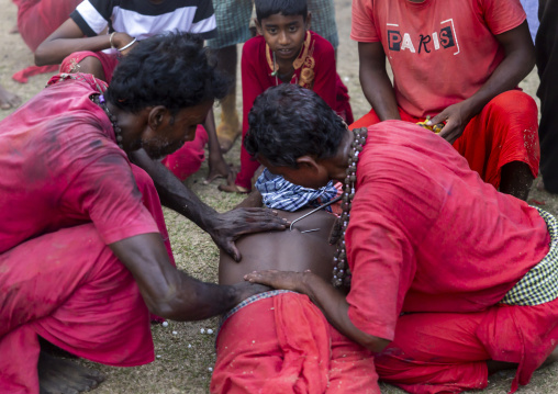 Men putting a hook in the back of a man for a body suspension in Charak Puja, Sylhet Division, Kamalganj, Bangladesh
