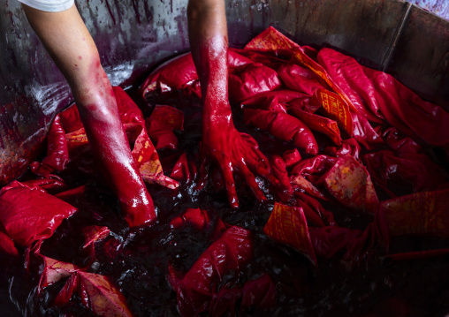 Bangladeshi man dyeing fabrics in red in a batik factory, Chittagong Division, Comilla, Bangladesh