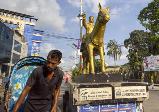 Rickshaw driving in front of a golden statue, Chittagong Division, Chittagong, Bangladesh