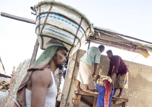 Bangladeshi men weighing baskets with salt at a factory, Chittagong Division, Chittagong, Bangladesh