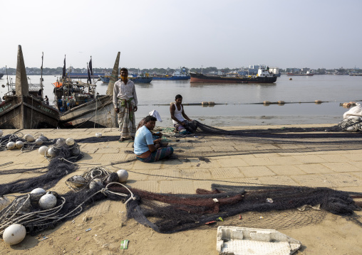 Bangladeshi men repairing fishing nets in the fish market, Chittagong Division, Chittagong, Bangladesh