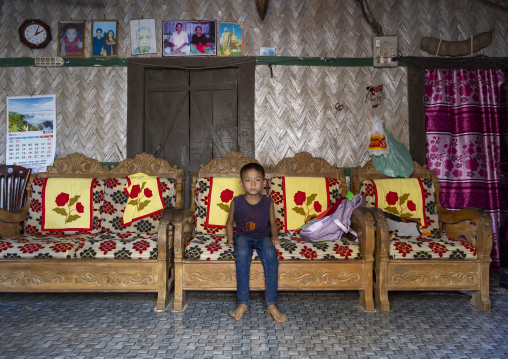 Portrait of a Tanchangya ethnic group boy sit on a couch inside his house, Chittagong Division, Bandarban, Bangladesh