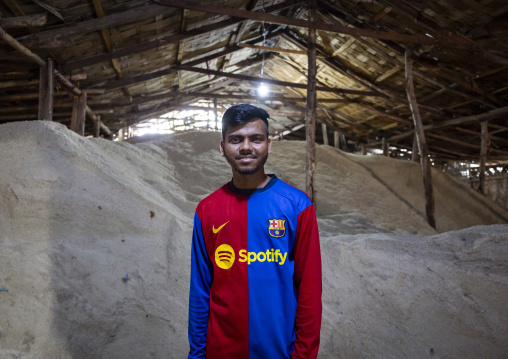 Man with a Barcelona football shirt working in a salt factory, Chittagong Division, Chittagong, Bangladesh