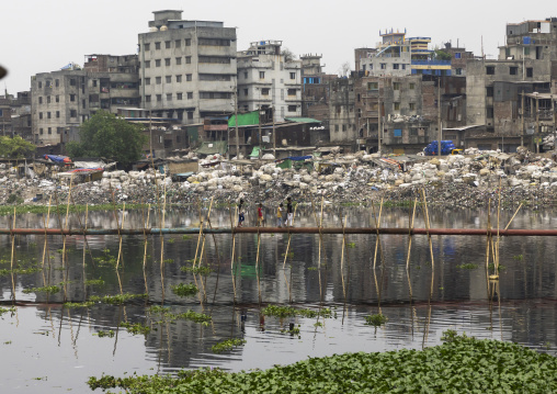 Bangladeshi children walking on a pipeline above a lake, Dhaka Division, Dhaka, Bangladesh