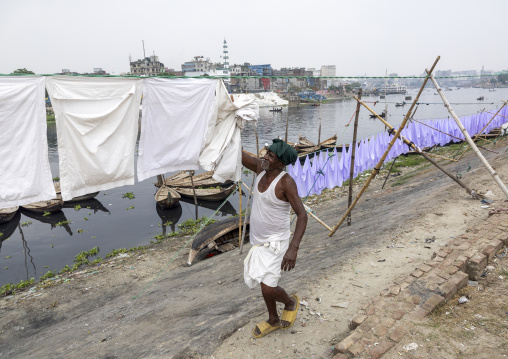 Man taking off household linens hanging on clothesline, Dhaka Division, Keraniganj, Bangladesh