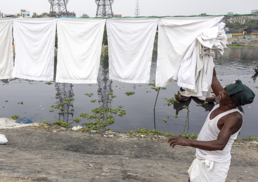 Man taking off household linens hanging on clothesline, Dhaka Division, Keraniganj, Bangladesh