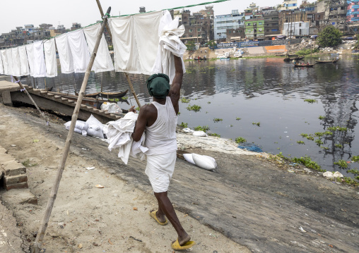 Man taking off household linens hanging on clothesline, Dhaka Division, Keraniganj, Bangladesh