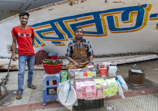 Man selling cigarettes in front of anchored ferry vessels at the dockyard, Dhaka Division, Dhaka, Bangladesh
