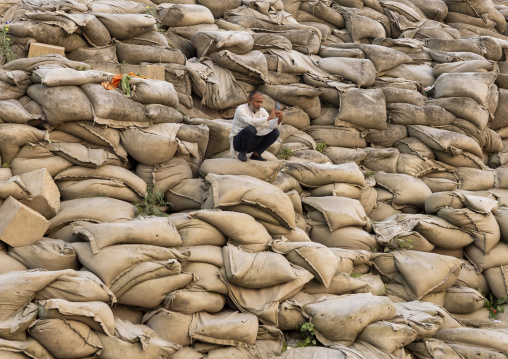 Man sit on bags filled with sand to prevent from erosion, Rajshahi Division, Rajshahi, Bangladesh