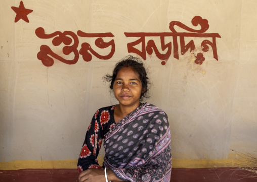 Christian girl from Santal ethnic group below Merry Christmas on the wall, Rajshahi Division, Tanore, Bangladesh