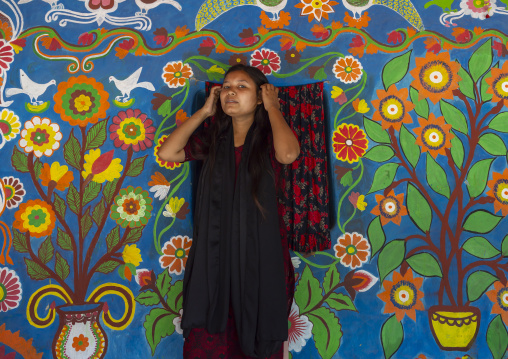 Bangladeshi woman in front of a traditional wall painting in a house, Rajshahi Division, Tikoil, Bangladesh