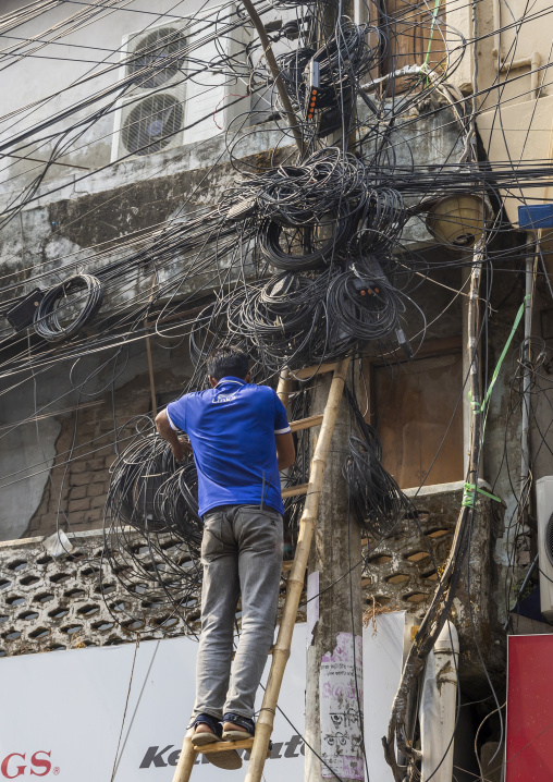 Man fixing tngled wires hanging on electricity pole, Khulna Division, Jessore, Bangladesh