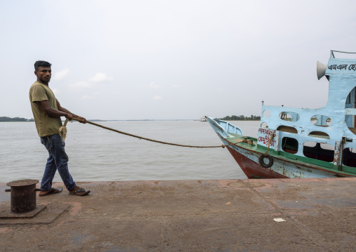 Bangladeshi man pulling anchoring ferry vessel, Barisal Division, Barisal, Bangladesh