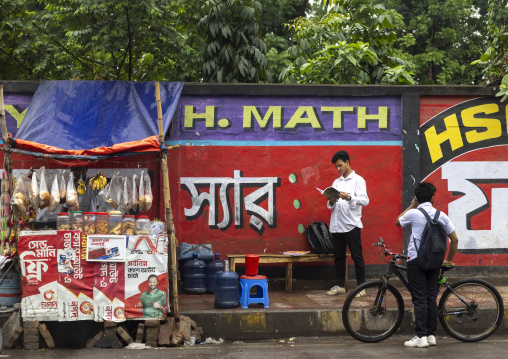 Bangladeshi man reading a book near a street food stall, Dhaka Division, Dhaka, Bangladesh