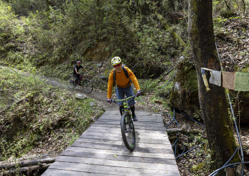 Men ride on a sports bicycle in Kuenselphodrang Nature Park, Chang Gewog, Thimphu, Bhutan