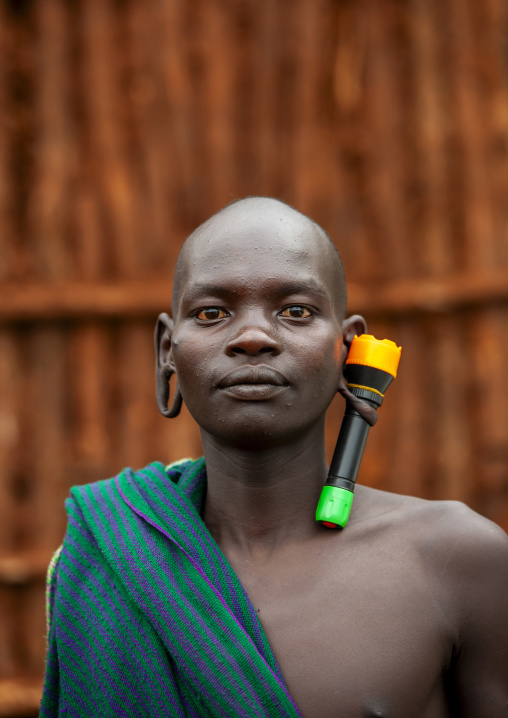 Suri tribe man with an enlarged ear decorated with a lamp, Kibish, Omo valley, Ethiopia