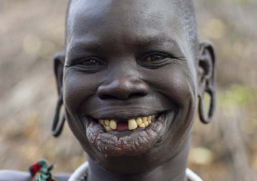 Smiling surma tribe woman with enlarged lip and ears, Omo valley, Tulgit, Ethiopia