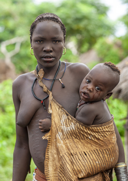 Portrait of a Bodi tribe mother carrying her baby, Hana Mursi, Omo valley, Ethiopia