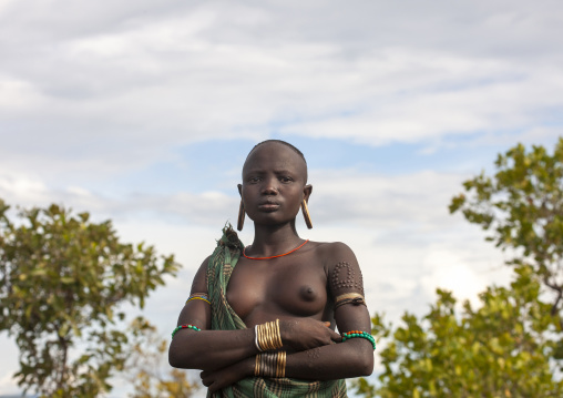Mursi tribe woman with ear plates and scarifications, Omo valley, Mago National Park, Ethiopia