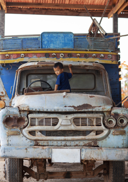 Boy playing in an old car, Khammouane province, Thakhek, Laos