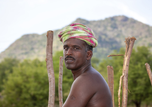 Shirtless man wearing a turban posing next to wooden stick, Tamil Nadu, Madurai, India