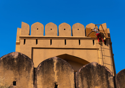 Indian man painting Amber Fort rampart, Rajasthan, Amer, India