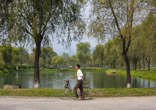 North Korean man with a bicycle on the banks of a lake, North Hwanghae, Sariwon, North Korea
