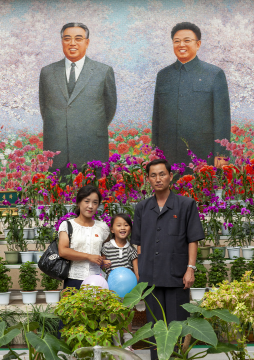 Family posing in front of the Leaders at the international Kimilsungia festival, DGC, Pyongyang, North Korea
