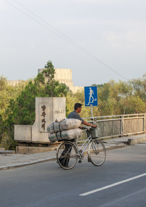 North Korean man pushing a loaded bicycle in town, DGC, Pyongyang, North Korea