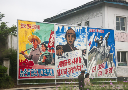 North Korean people passing in front of propaganda billboards, South Hamgyong, Hamhung, North Korea
