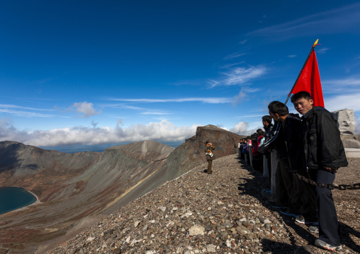 Group of students with red flag in front of lake at mount Paektu, Ryanggang, Mount Paektu, North Korea